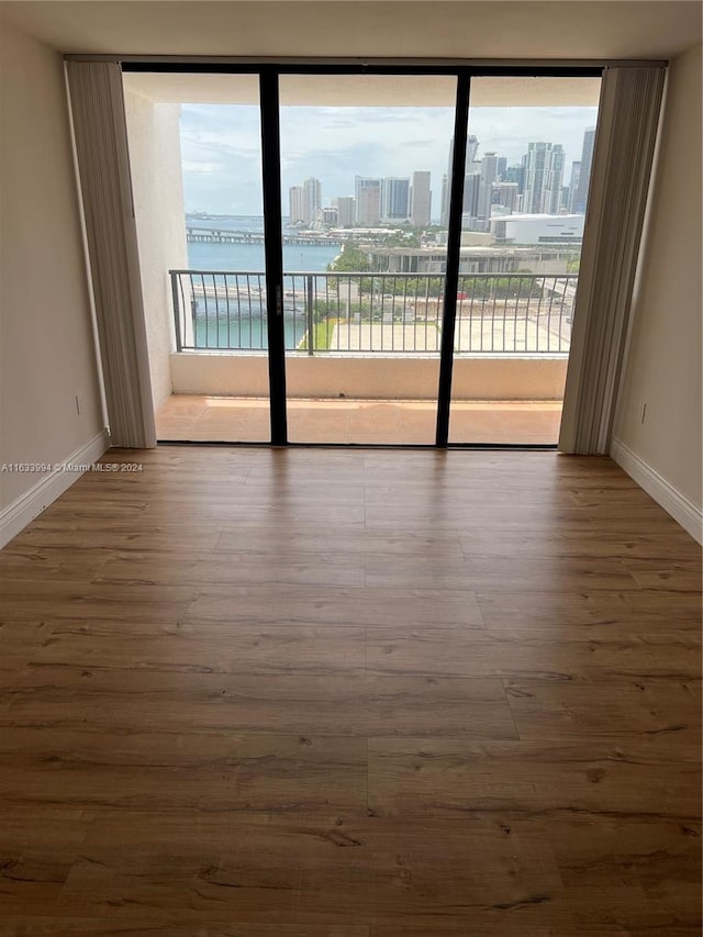 unfurnished room with a water view, hardwood / wood-style floors, and plenty of natural light