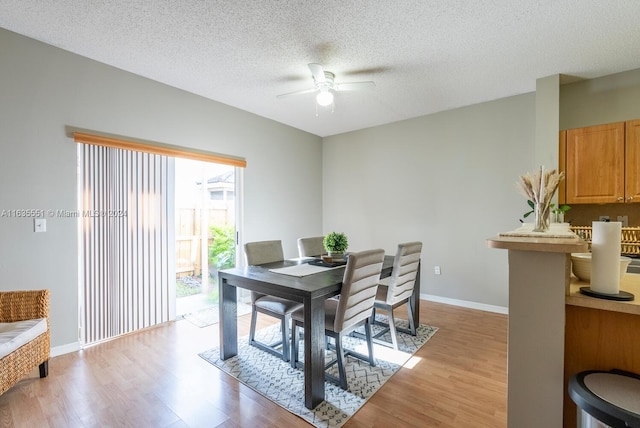 dining area with a textured ceiling, ceiling fan, and light wood-type flooring