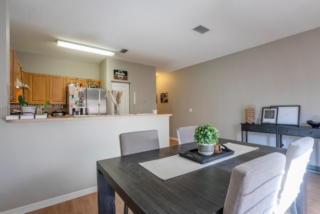 dining space featuring a textured ceiling and light hardwood / wood-style flooring