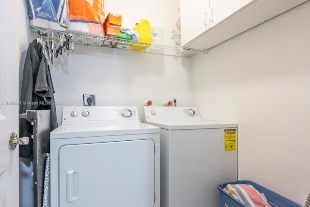 clothes washing area featuring independent washer and dryer and cabinets