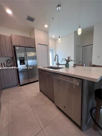 kitchen featuring a kitchen bar, pendant lighting, a center island with sink, and stainless steel appliances