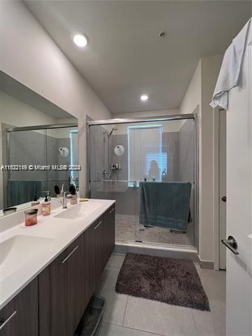 bathroom with tile patterned flooring, double vanity, and a shower with door