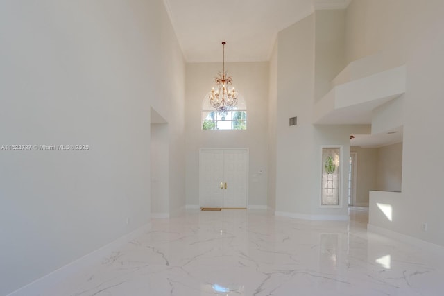 foyer featuring a towering ceiling, ornamental molding, and an inviting chandelier