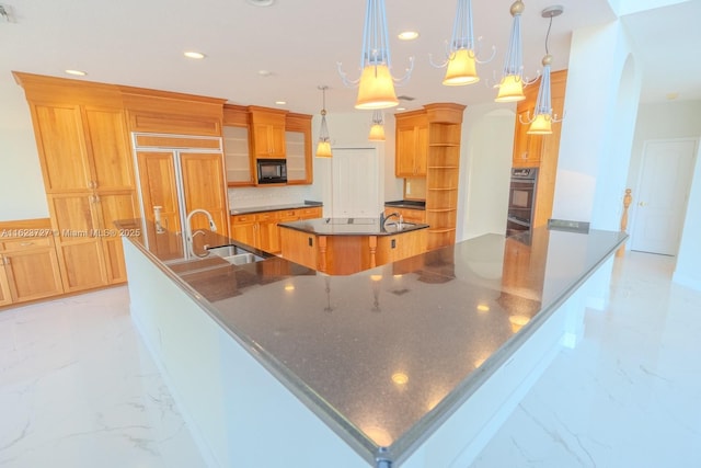 kitchen featuring pendant lighting, backsplash, black appliances, sink, and a large island