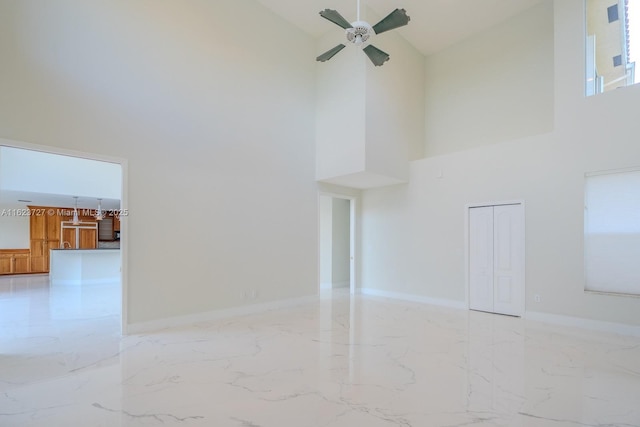 unfurnished living room with ceiling fan and a high ceiling