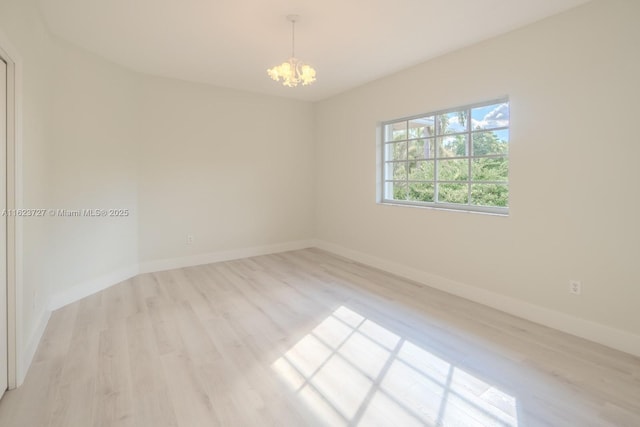 spare room featuring light hardwood / wood-style floors and an inviting chandelier