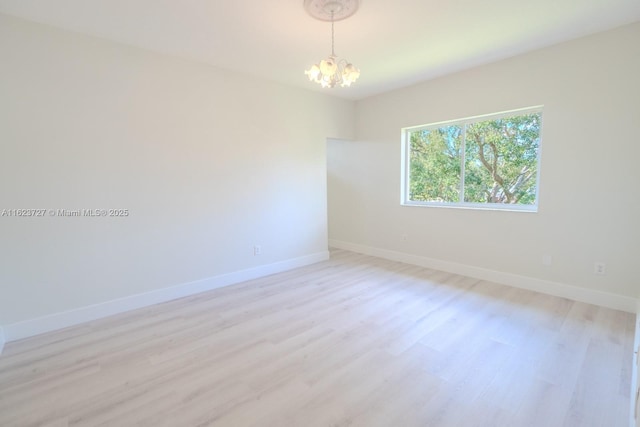 spare room featuring a notable chandelier and light hardwood / wood-style floors