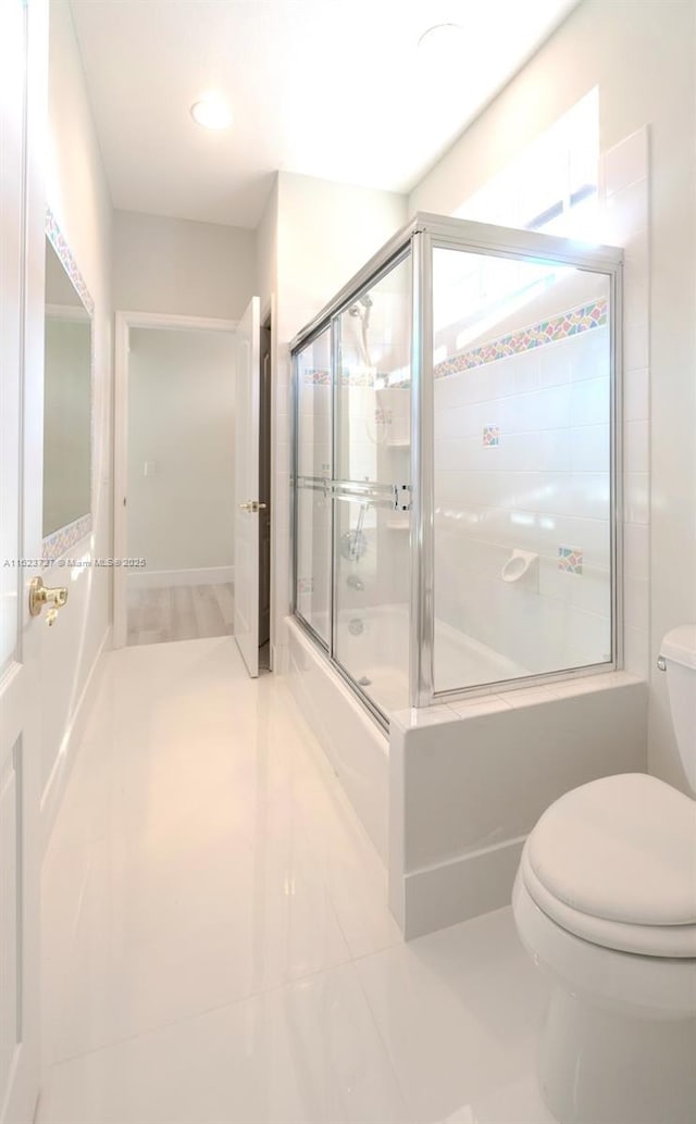 bathroom featuring tile patterned floors, toilet, and bath / shower combo with glass door