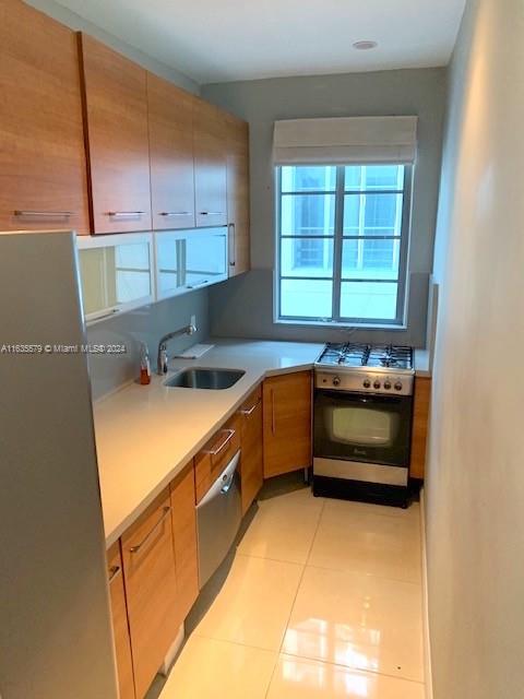 kitchen featuring white range with electric cooktop, sink, stainless steel refrigerator, and light tile patterned floors