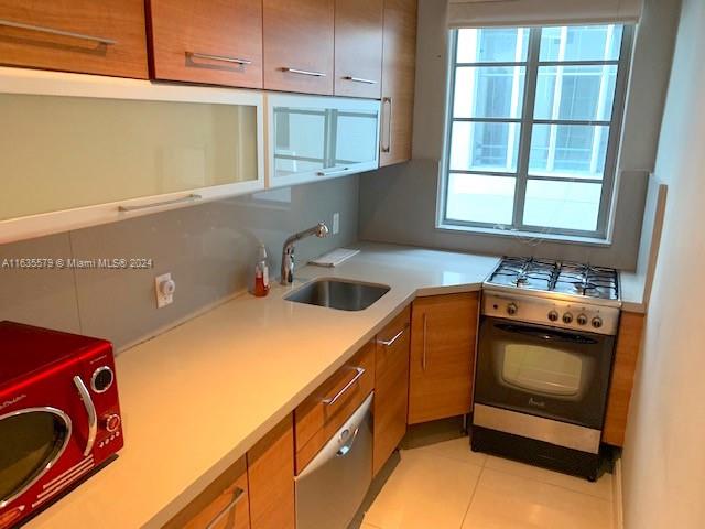 kitchen with wall oven, sink, light tile patterned floors, and plenty of natural light