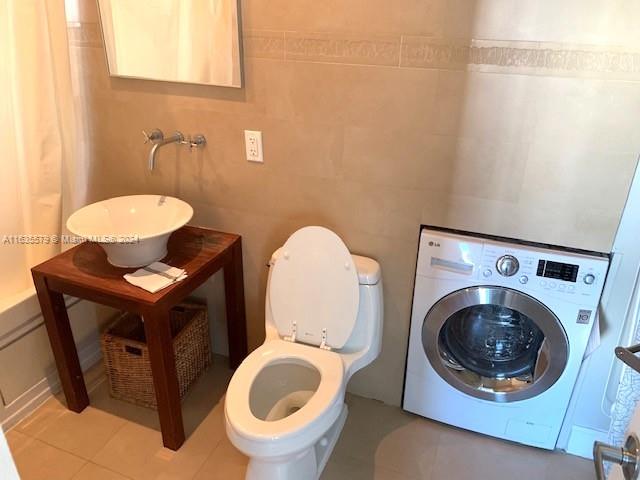 bathroom with washer / clothes dryer, tile patterned flooring, toilet, and sink