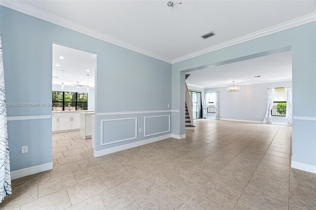 tiled spare room featuring a chandelier and crown molding