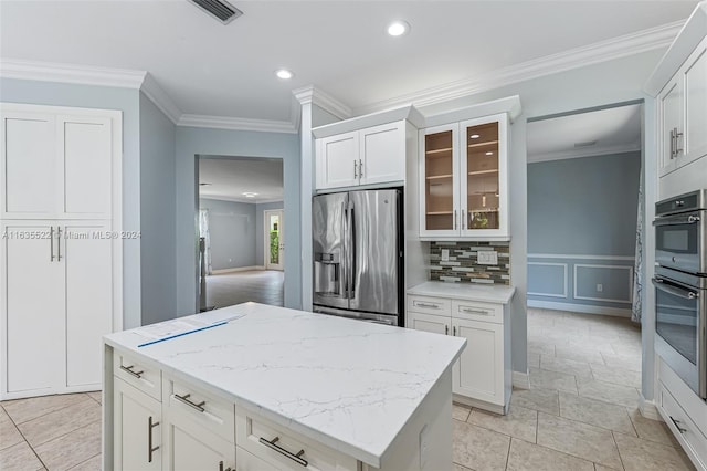 kitchen featuring decorative backsplash, appliances with stainless steel finishes, light tile patterned floors, and white cabinets