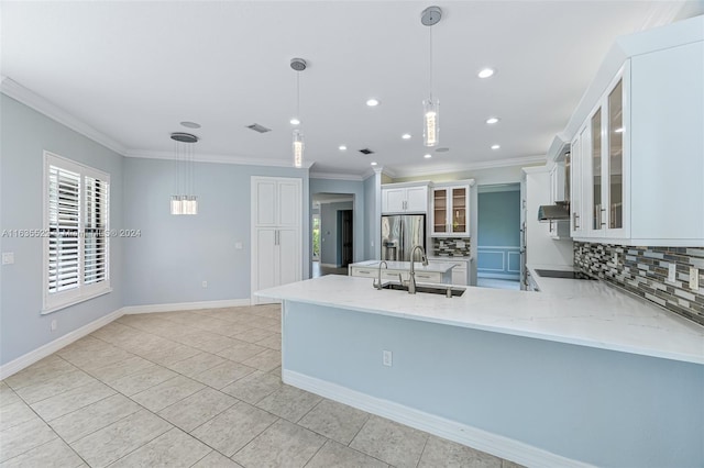 kitchen with decorative backsplash, white cabinetry, stainless steel fridge, and decorative light fixtures