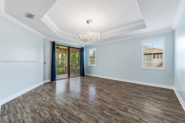 empty room featuring a raised ceiling, dark hardwood / wood-style flooring, and ornamental molding