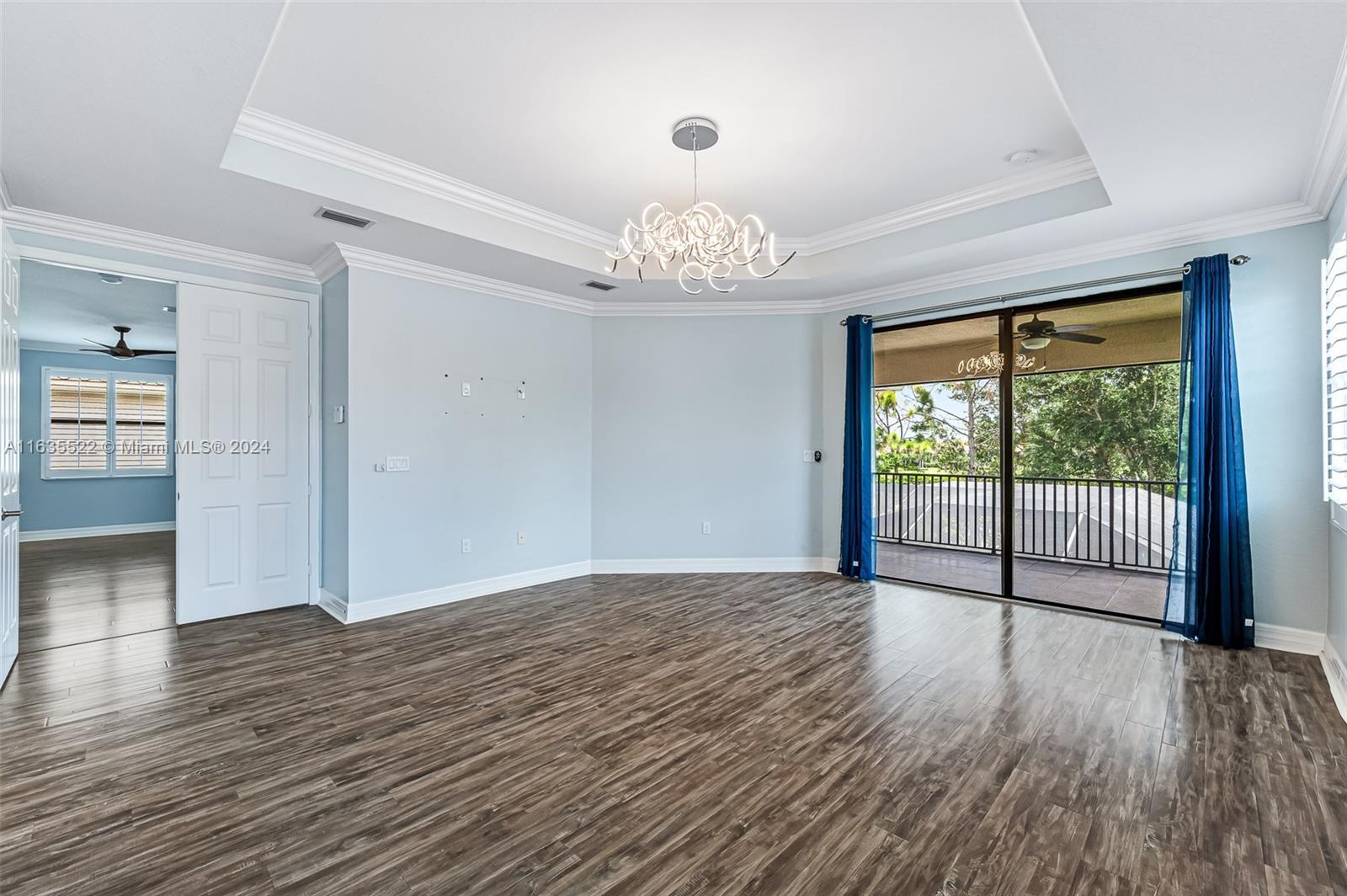 unfurnished room with a wealth of natural light, ceiling fan with notable chandelier, and a raised ceiling