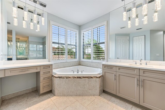 bathroom featuring tile patterned flooring, tiled bath, and vanity