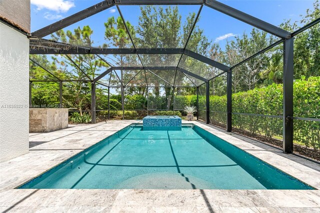 view of swimming pool featuring a patio and glass enclosure