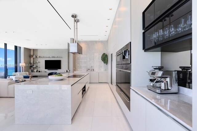 17141 Collins Ave Unit 2501, Sunny Isles Beach, FL 33160 - kitchen featuring a spacious island, black appliances, white cabinetry, a wall of windows, and a water view