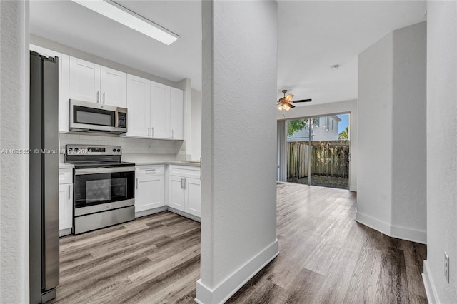 kitchen featuring appliances with stainless steel finishes, light wood-type flooring, ceiling fan, and tasteful backsplash