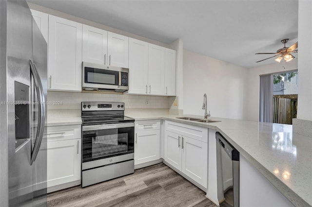 kitchen featuring stainless steel appliances, backsplash, light wood-type flooring, light stone countertops, and ceiling fan