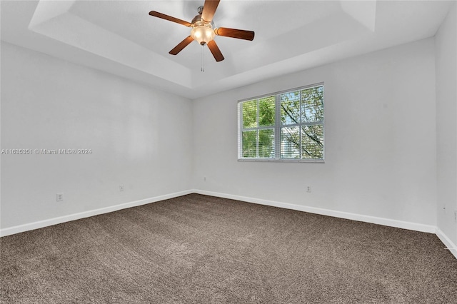 carpeted empty room with ceiling fan and a tray ceiling