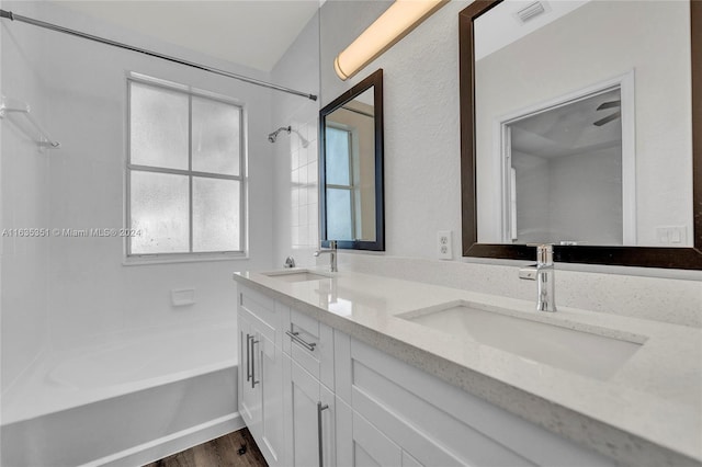 bathroom with washtub / shower combination, wood-type flooring, and double sink vanity