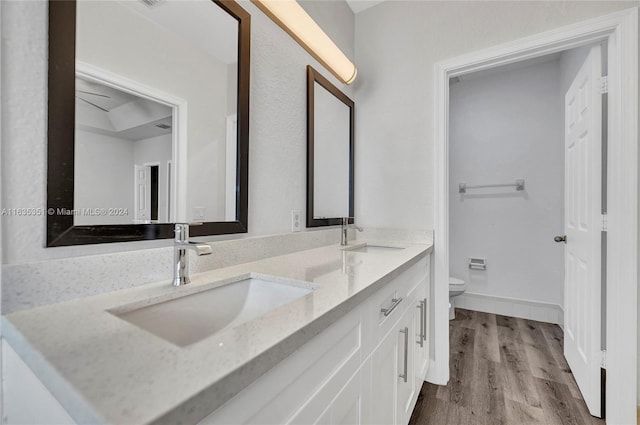 bathroom with double vanity, wood-type flooring, and toilet