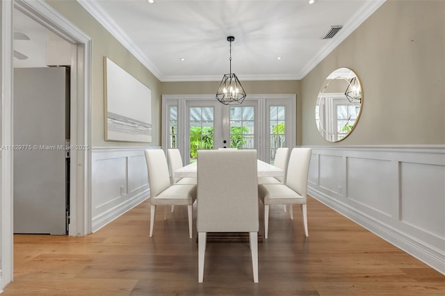 dining area with a chandelier, french doors, light hardwood / wood-style flooring, and ornamental molding