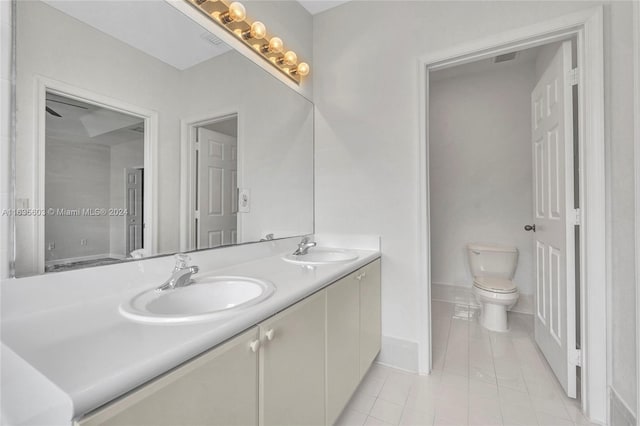 bathroom featuring toilet, tile patterned flooring, and double vanity