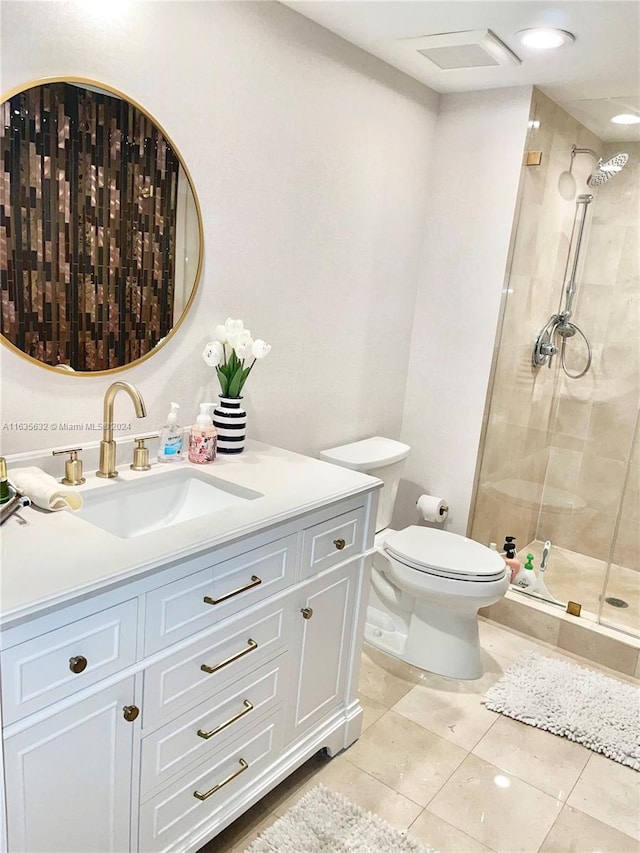 bathroom with tile patterned floors, vanity, a shower with shower door, and toilet