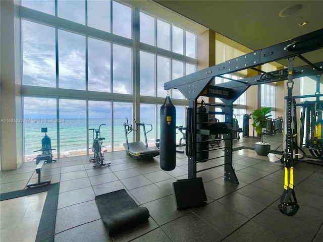 workout area with a water view, expansive windows, plenty of natural light, and a high ceiling