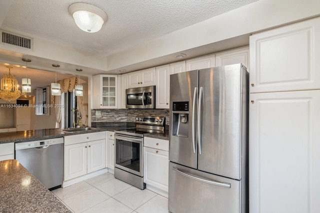 kitchen featuring visible vents, backsplash, glass insert cabinets, appliances with stainless steel finishes, and a sink