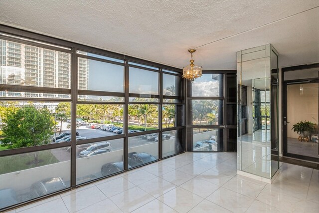 kitchen with sink, stainless steel refrigerator, white cabinetry, hanging light fixtures, and floor to ceiling windows