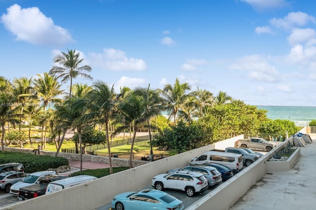 uncovered parking lot featuring a water view and fence