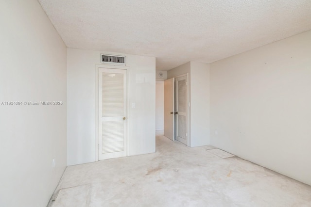 unfurnished room with visible vents, a textured ceiling, and carpet floors