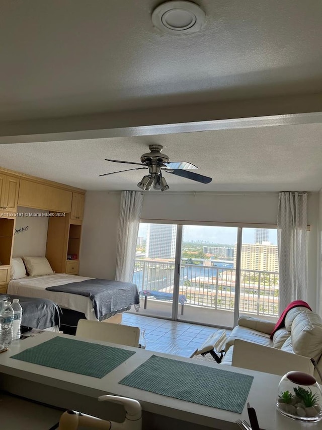 bedroom with light tile patterned floors, access to outside, a ceiling fan, and a textured ceiling