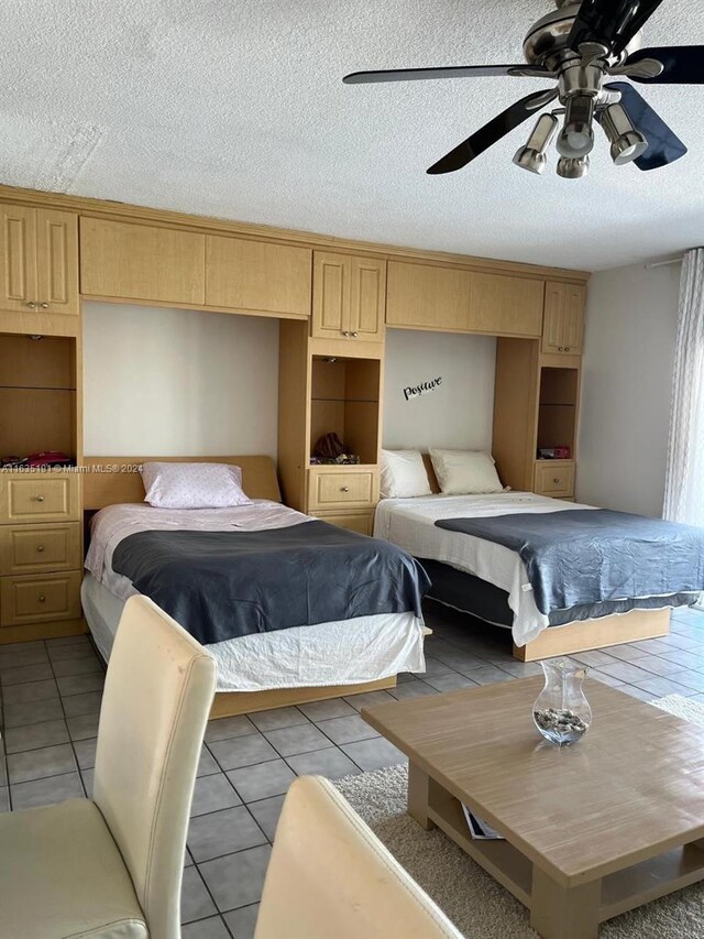 tiled bedroom with a textured ceiling and ceiling fan