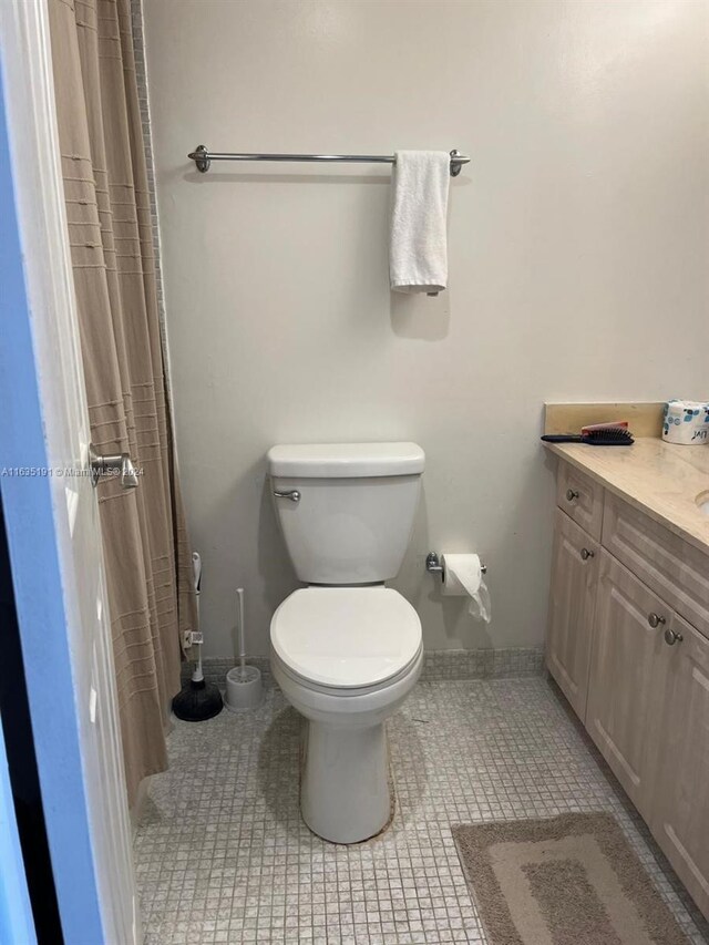 bathroom with toilet, vanity, and tile patterned floors