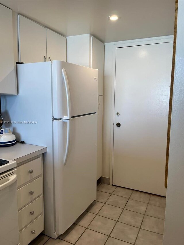 kitchen with light tile patterned floors, white appliances, and white cabinets