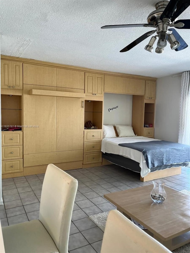 bedroom featuring ceiling fan, a closet, a textured ceiling, and light tile patterned floors