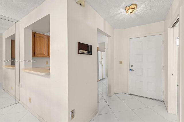 corridor featuring light tile patterned flooring and a textured ceiling