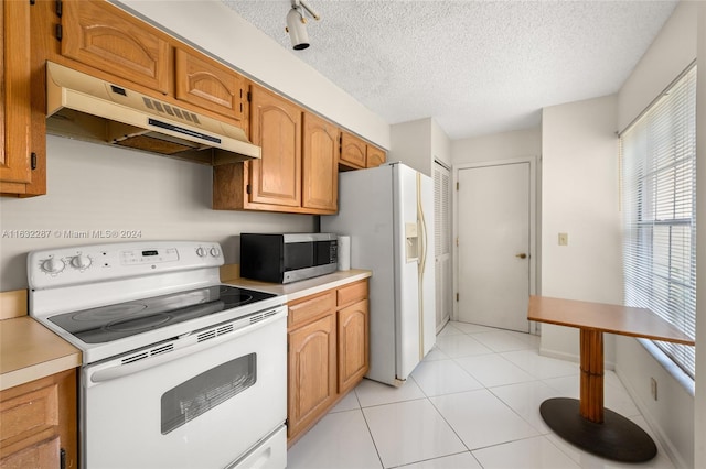 kitchen featuring light tile patterned flooring, track lighting, white appliances, and a textured ceiling