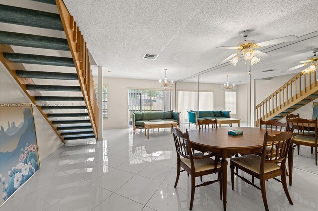 tiled dining space featuring a textured ceiling and ceiling fan with notable chandelier