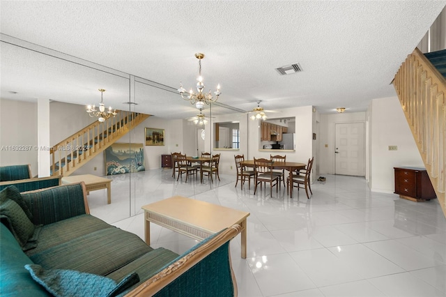 living room with a textured ceiling, light tile patterned flooring, and ceiling fan with notable chandelier