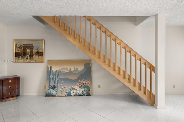 stairway featuring tile patterned floors and a textured ceiling