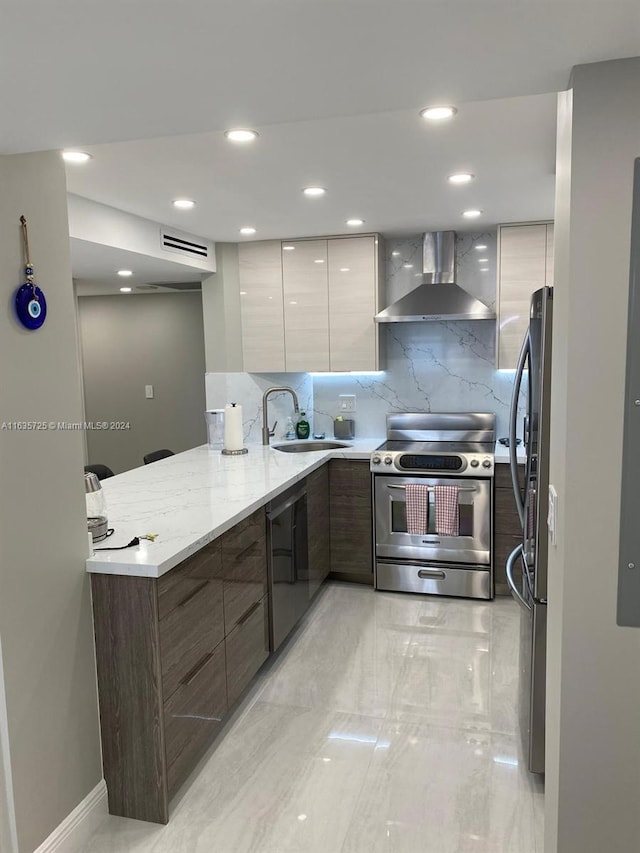 kitchen featuring light stone countertops, stainless steel appliances, decorative backsplash, wall chimney range hood, and white cabinets