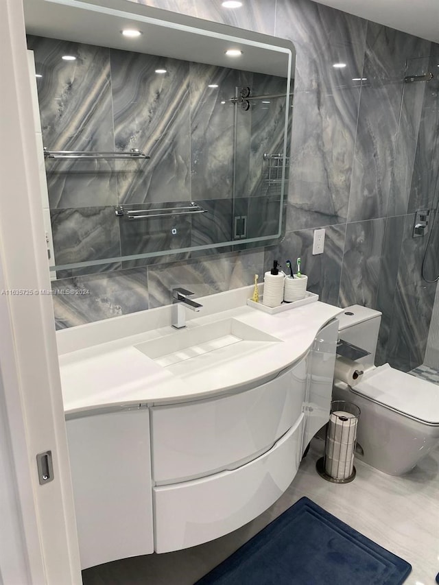 bathroom featuring vanity, tiled shower, tile walls, toilet, and tile patterned floors