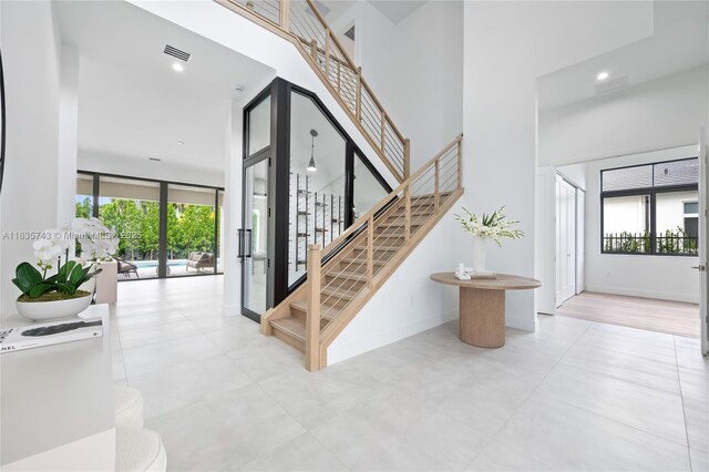 stairway with baseboards, a high ceiling, visible vents, and recessed lighting