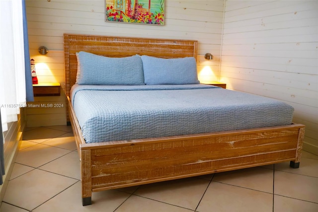 bedroom with tile patterned flooring and wooden walls